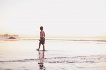 Молодий хлопчик на заході сонця на пляжі — стокове фото