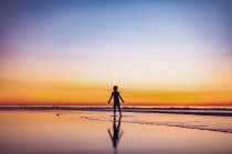 Молодий хлопчик на заході сонця на пляжі — стокове фото