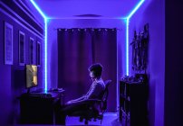 El muchacho joven con el ordenador en la habitación - foto de stock