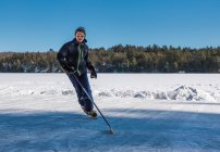 Teen boy playing hockey on an outdoor rink on a frozen lake in Canada. — Stock Photo