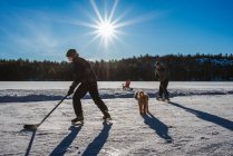 Father and son playing hockey on outdoor rink on frozen Canadian lake. — Stock Photo
