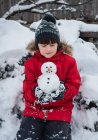 Le garçon avec bonhomme de neige dans la forêt enneigée — Photo de stock