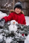 Мальчик со снеговиком в заснеженном лесу — стоковое фото