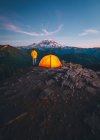 View of a  woman and camping tent on a background of mountains and the moon — Stock Photo