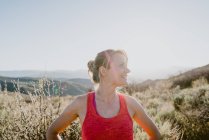 Mulher loira atlética ri com sol e montanhas atrás dela — Fotografia de Stock
