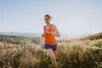 Sendero atlético de mujer rubia corre en las montañas a la hora dorada - foto de stock