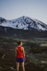 Молода жінка дивиться на гори в той час як стежка біжить в сутінках — стокове фото