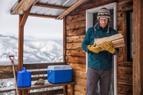 Ein Mann sammelt Brennholz vor seiner Hütte in den Bergen — Stockfoto