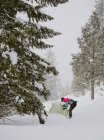 Чоловік у яскравій куртці стоїть над наметом у глибокому снігу — стокове фото
