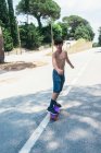 Ritratto di allegro skateboard adolescente senza maglietta su strada di montagna — Foto stock