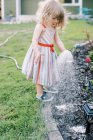 Little girl watering plants  in the backyard — Stock Photo