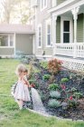 Маленькая девочка поливает растения на заднем дворе — стоковое фото