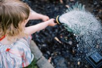 Bambina annaffiare le piante nel cortile — Foto stock