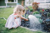 Petite fille arrosage plantes dans la cour arrière — Photo de stock