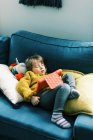 Niña en colores primarios durmiendo en sofá con tablet - foto de stock