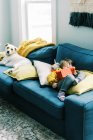 Petite fille tout-petit aux couleurs primaires dormant sur canapé avec tablette — Photo de stock