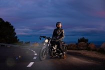 Motociclista em sua moto choper à noite na estrada — Fotografia de Stock