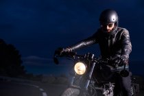 Motociclista em sua moto choper à noite na estrada — Fotografia de Stock