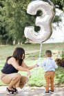 Mom and her little boy with a birthday balloon in the park — Stock Photo