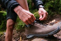 Крупним планом молодий чоловік зв'язує її взуття під час походу — стокове фото