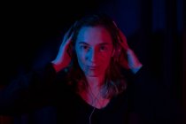 Portrait of woman with headphones set with red and blue neon lights. — Stock Photo