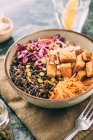 Tigela Budda com salada de arroz preto, salada de repolho vermelho, cenoura, tofu frito e brotos e pistácios picados — Fotografia de Stock