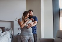 Recién nacido bebé siendo acunado por los nuevos padres en el centro de parto - foto de stock