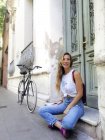 Щаслива жінка дивиться далеко, сидячи на велосипеді зовні будівлі — стокове фото