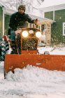 Чоловік на старовинному відновленому тракторі з 60-х років оранки снігу в штормі — стокове фото