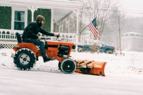 Homem em um trator vintage restaurado da década de 60 arar neve em uma tempestade — Fotografia de Stock
