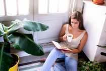 Young beautiful woman reading book in living room — Stock Photo