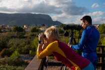 Pareja joven de observadores de aves usando prismáticos y telescopio, Calpe, provincia de Alicante, Costa Blanca, España - foto de stock