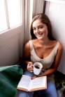 Junge schöne Frau liest Buch im Wohnzimmer — Stockfoto