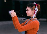 Молода жінка налаштовує фотоапарат, міську сцену — стокове фото