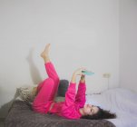 Молода дівчина лежить на дивані зі смартфоном — стокове фото