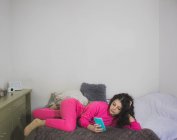 Jeune fille couchée sur le canapé avec smartphone — Photo de stock