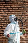 Un homme en costume de virus EPI et un masque à gaz sur son visage avec la ville en arrière-plan — Photo de stock