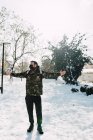 Молодой человек раскрывает объятия и носит медицинскую защитную маску в снегу — стоковое фото