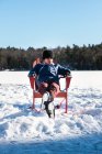 Adolescente chico tomando un descanso de patinar en pista al aire libre en el día de invierno. - foto de stock