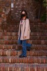 Природная молодая женщина в маске спускается по лестнице старой городской постройки — стоковое фото