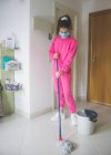 Jeune femme en masque médical nettoyage sol — Photo de stock