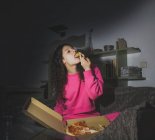 Молода дівчина сидить сама і їсть піцу — стокове фото
