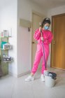 Jeune femme en masque médical nettoyage sol — Photo de stock