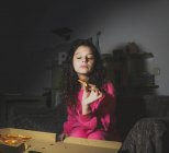Una joven sentada sola y comiendo pizza - foto de stock