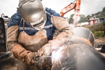 Men welding a water pipe outdoors with protective clothes — Stock Photo