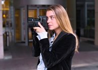 Привлекательная молодая девушка ждет с фотоаппаратом перед дверью отеля — стоковое фото