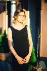 Junge Frau in schwarzem Kleid und Brille in der sonnigen Stadt — Stockfoto
