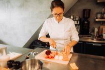 Köchin schneidet Gemüse in Restaurantküche — Stockfoto