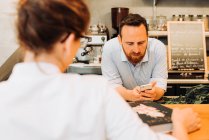 Lebensstil im Restaurant. Männlicher Koch, der sein Telefon benutzt, steht an der Bar — Stockfoto