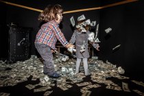Meninas se divertindo juntas enquanto joga contas de dinheiro para o ar — Fotografia de Stock